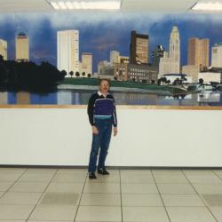 Photograph of William (bc) (Bill) Collins in Front of his Painting of the Columbus Skyline