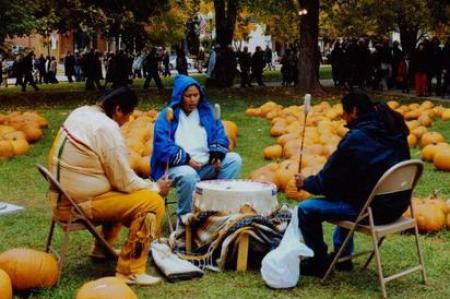 Morning Star Drum Group sits around drum in field of pumpkins