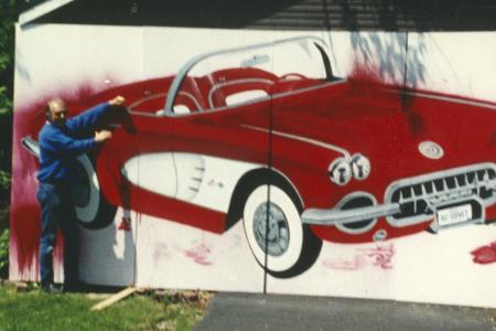 Photograph of William (bc) (Bill) Collins with his Painting of a Red Corvette